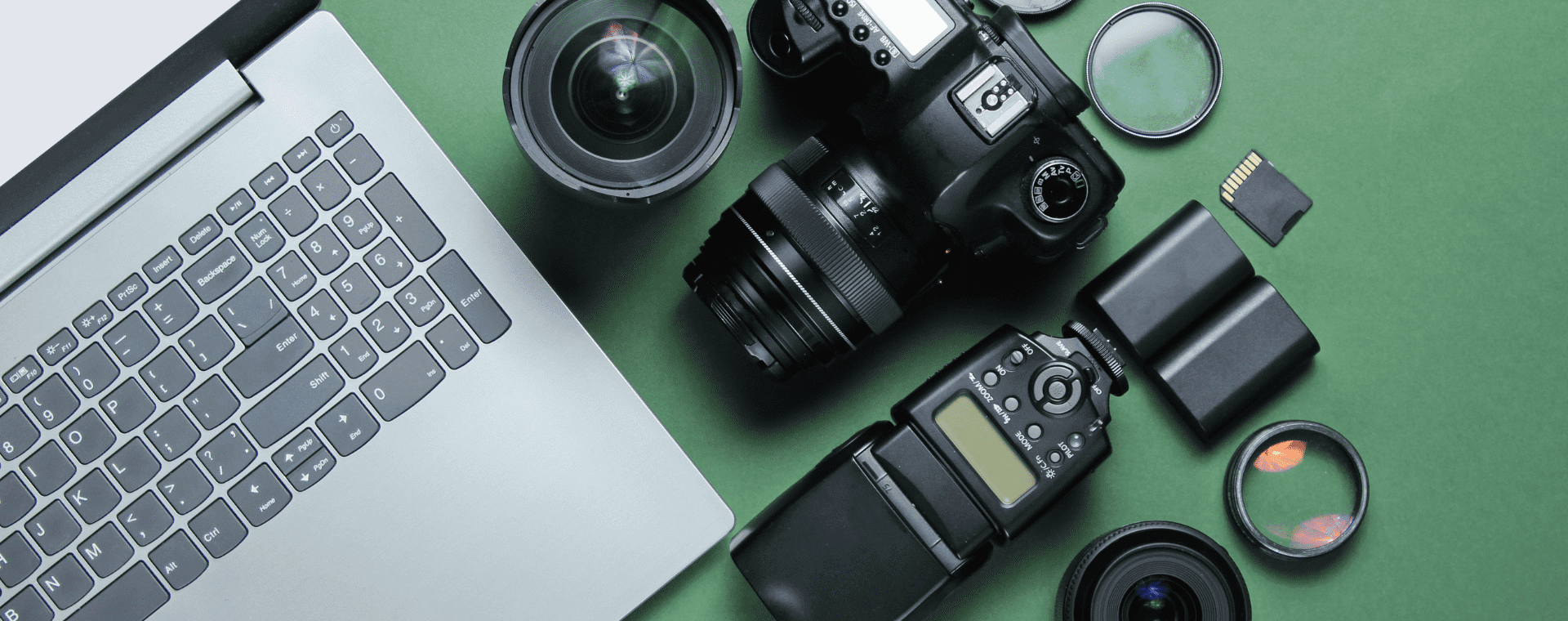 A laptop keyboard, a professional DSLR camera, camera lenses, memory cards, and lens filters are arranged on a green surface. The equipment suggests photography and digital editing work, with an emphasis on using 4K professional cameras for high-quality results.