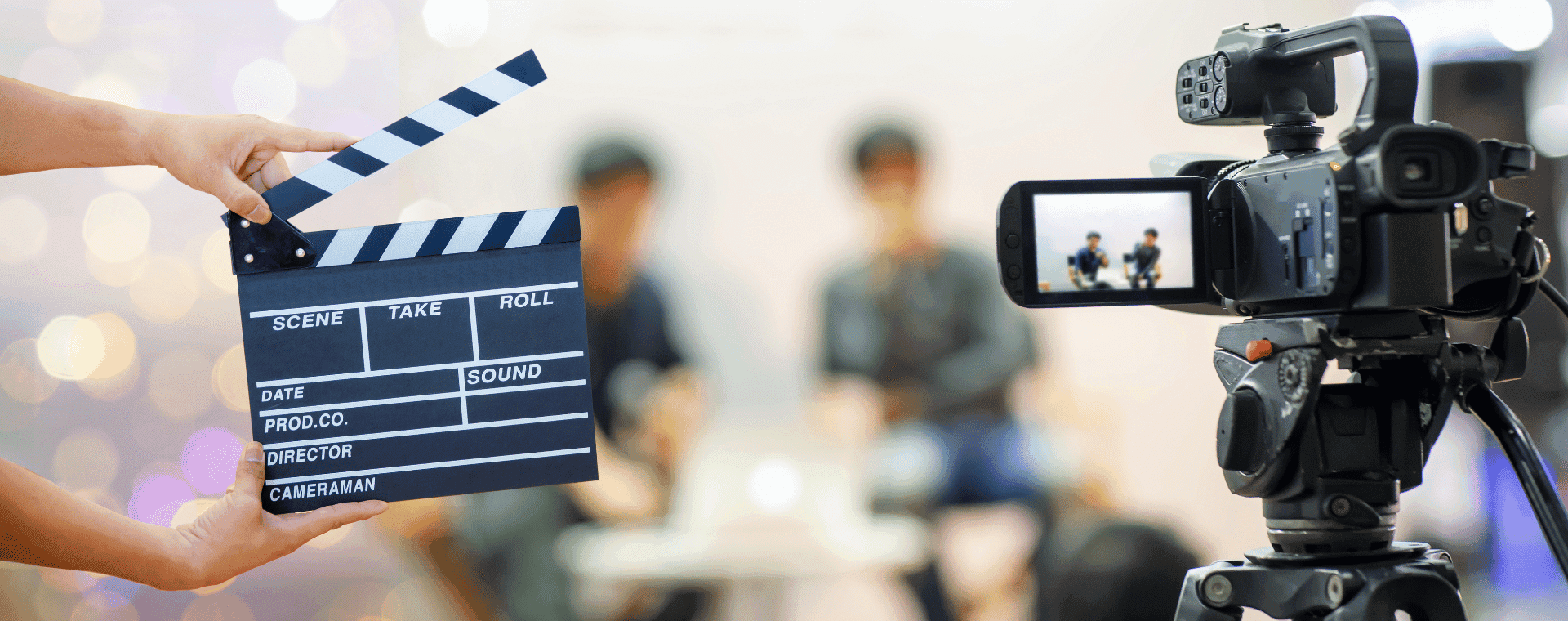 A close-up of a clapperboard being used in front of a camera, which is focused on two blurred individuals in the background. The clapperboard has sections for scene, take, roll, prod. co., director, and cameraman. The scene appears to be a video recording setup designed for enhanced video SEO.