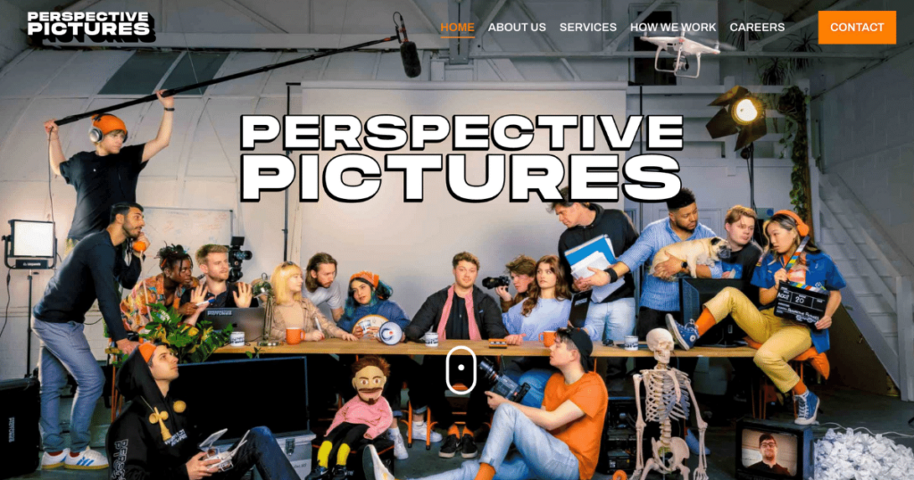 A Diverse Group Of People At A Cluttered Table In A Creative Studio, Some Holding Props And Equipment. A Large &Quot;Perspective Pictures&Quot; Sign Is Prominent, Reflecting Its Status As One Of The Top 10 Video Production Companies. The Scene Appears Busy And Dynamic, Suggesting A Collaborative Environment With Various Points Of Interest Filling The Space. A diverse group of people at a cluttered table in a creative studio, some holding props and equipment. A large "Perspective Pictures" sign is prominent, reflecting its status as one of the top 10 video production companies. The scene appears busy and dynamic, suggesting a collaborative environment with various points of interest filling the space.